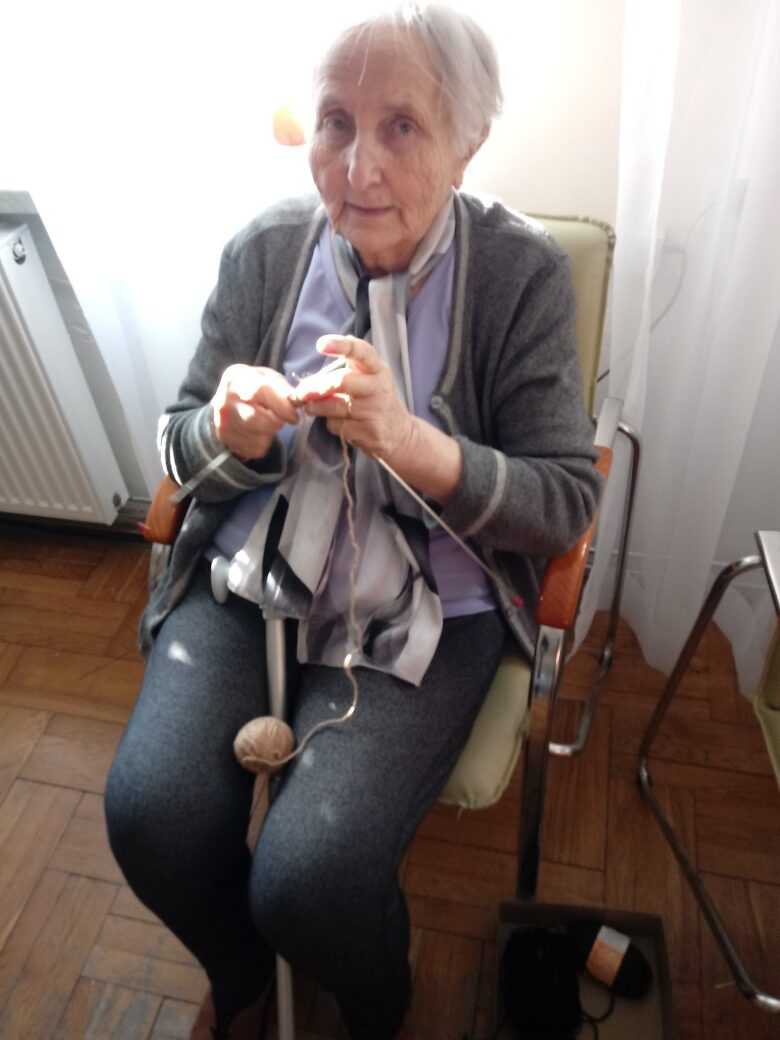mieszkanka DPS robi szalik na drutach