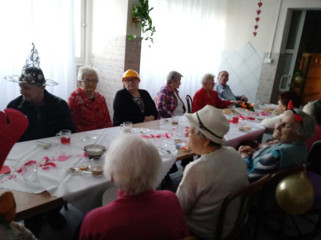 mieszkańcy podczas zabawy walentynkowej siedzą przy stołach w nietypowych przebraniach
