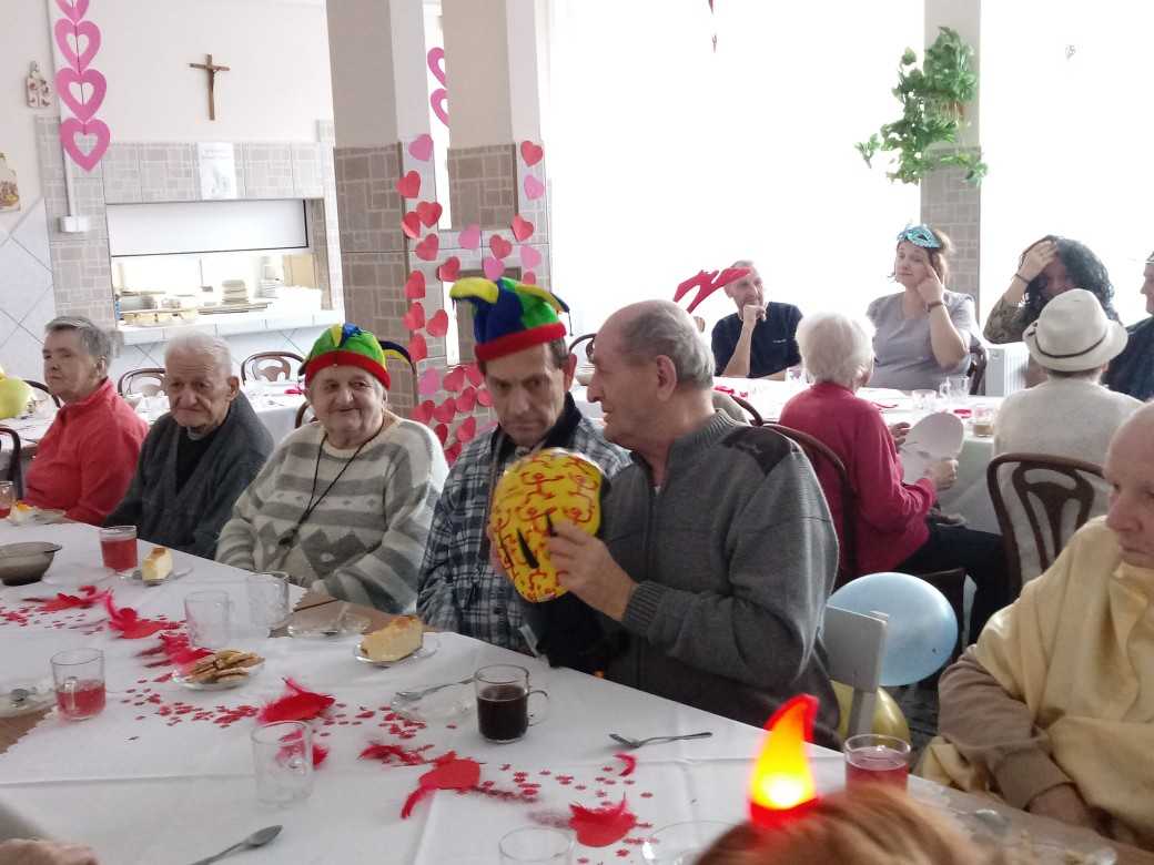 mieszkańcy podczas zabawy walentynkowej siedzą przy stołach i rozmawiają