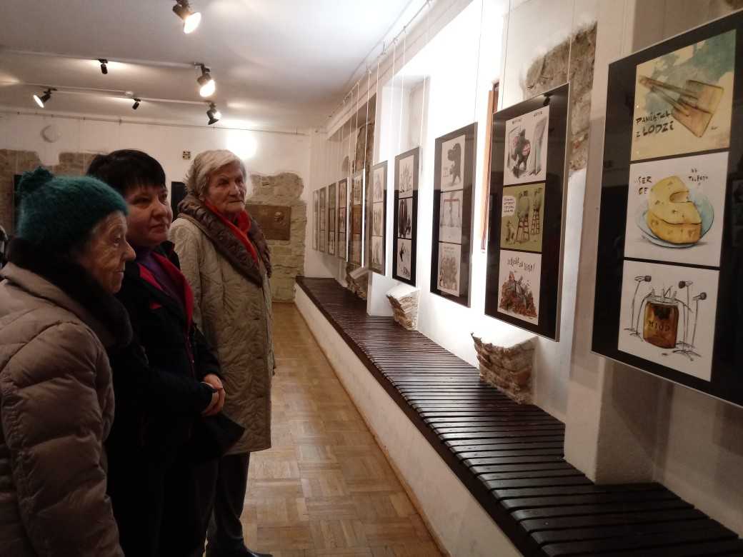 mieszkanki DPS oglądają prace karykaturzysty Bartłomieja Belniaka