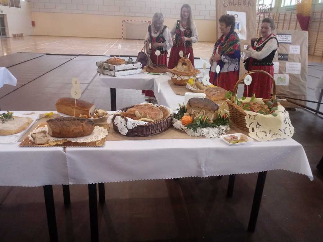 panie w strojach regionalnych oglądają chleby znajdujące się na stołach