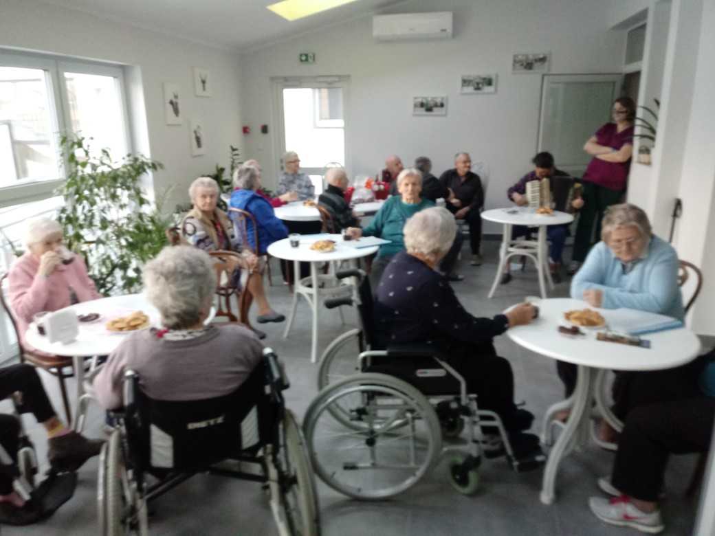 mieszkańcy DPS spędzają wspólnie czas w ogrodzie zimowym kolędując