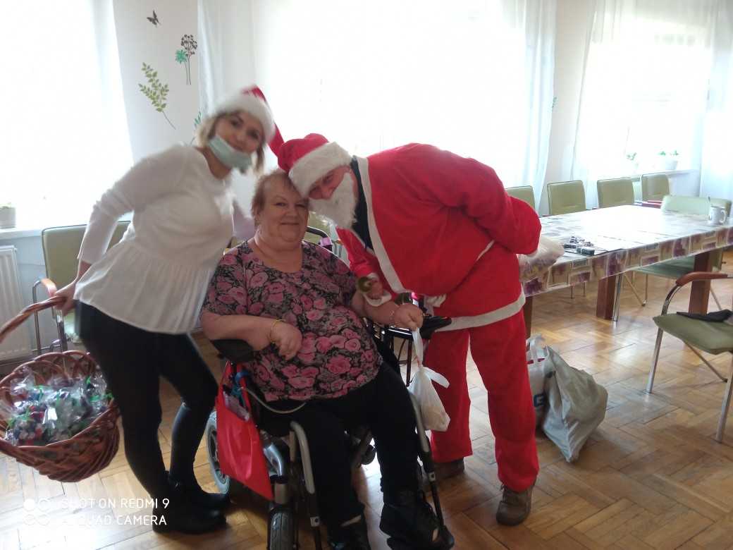 św. Mikołaj i śnieżynka pozują z mieszkanką DPS siedzącą na wózku inwalidzkim do pamiątkowego zdjęcia