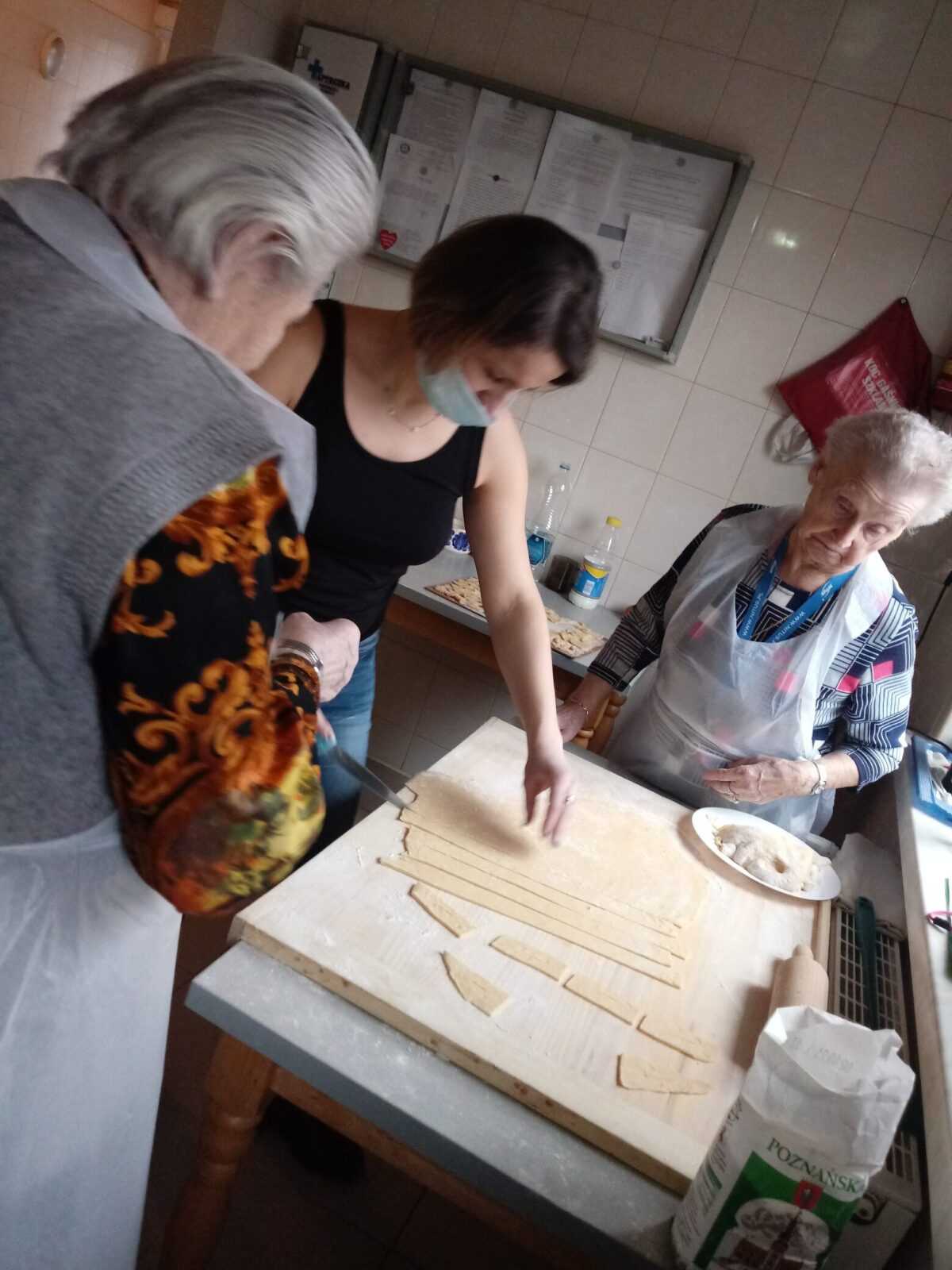 terapeuta zajęciowy i mieszkanki DPS przygotowują ciasto na chrust