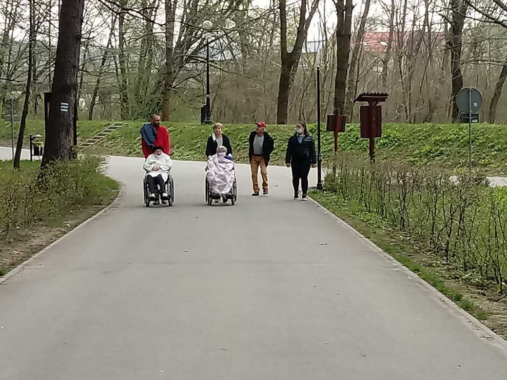 mieszkańcy i pracownicy DPS spacerują po parku i rozmawiają