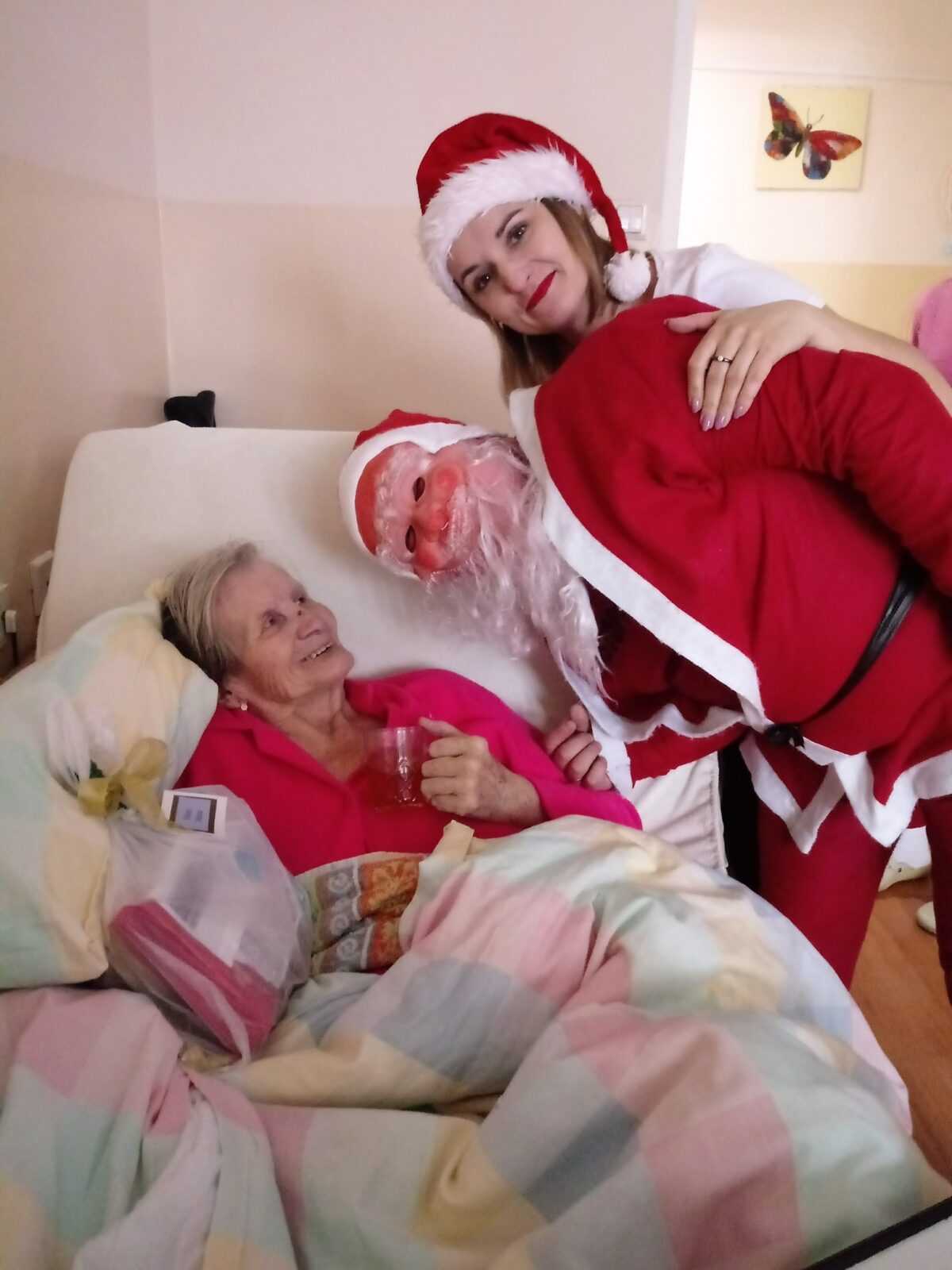 św. Mikołaj i śnieżynka wręczają upominek mieszkance DPS