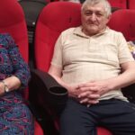 starsi ludzie siedzą na fotelach w kinie i uśmiechają się do zdjęcia