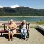 dwie starsze panie siedzą na ławce przy jeziorze